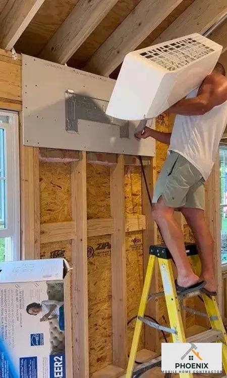 Contractor mounting ductless mini-split AC unit in mobile home for energy-efficient cooling